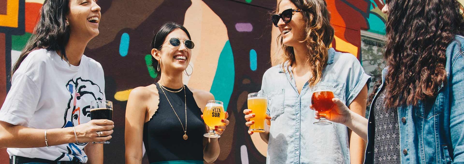 Friends having drinks in front of a colorful mural wall